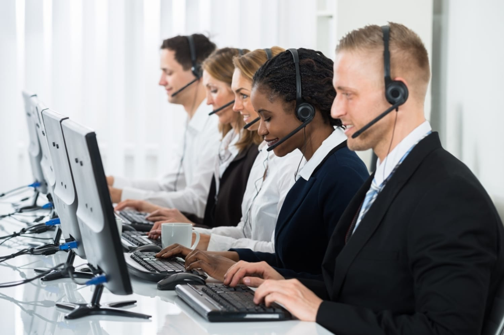 Five people using a call centre dialler on computers and headsets