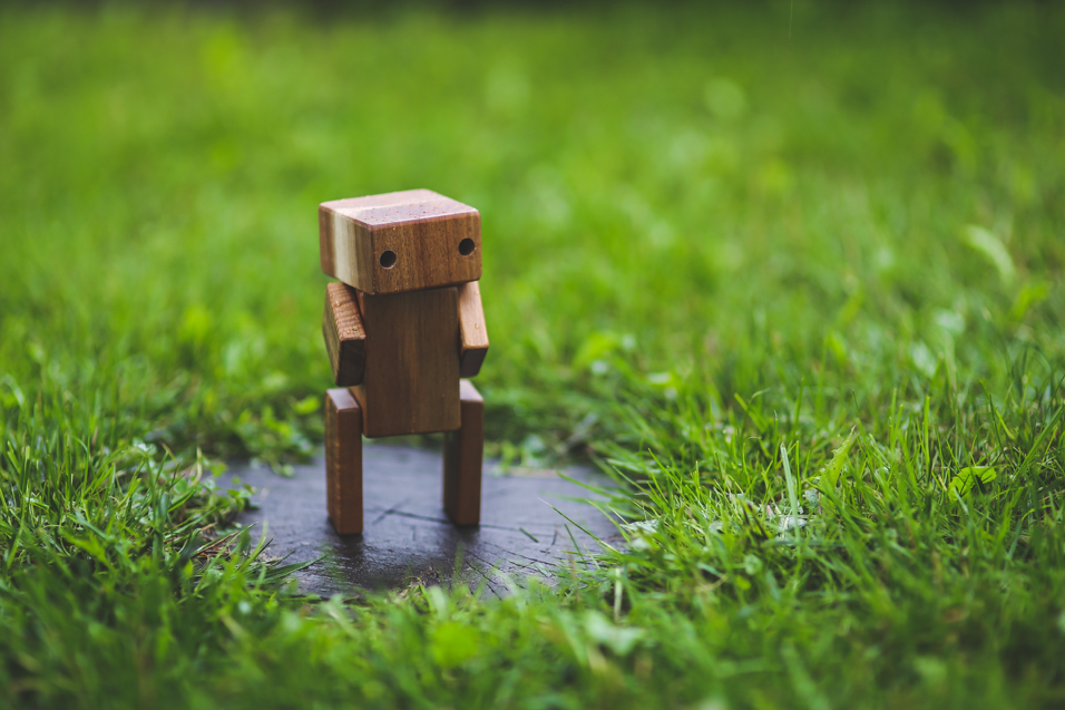 A wooden robot in the grass