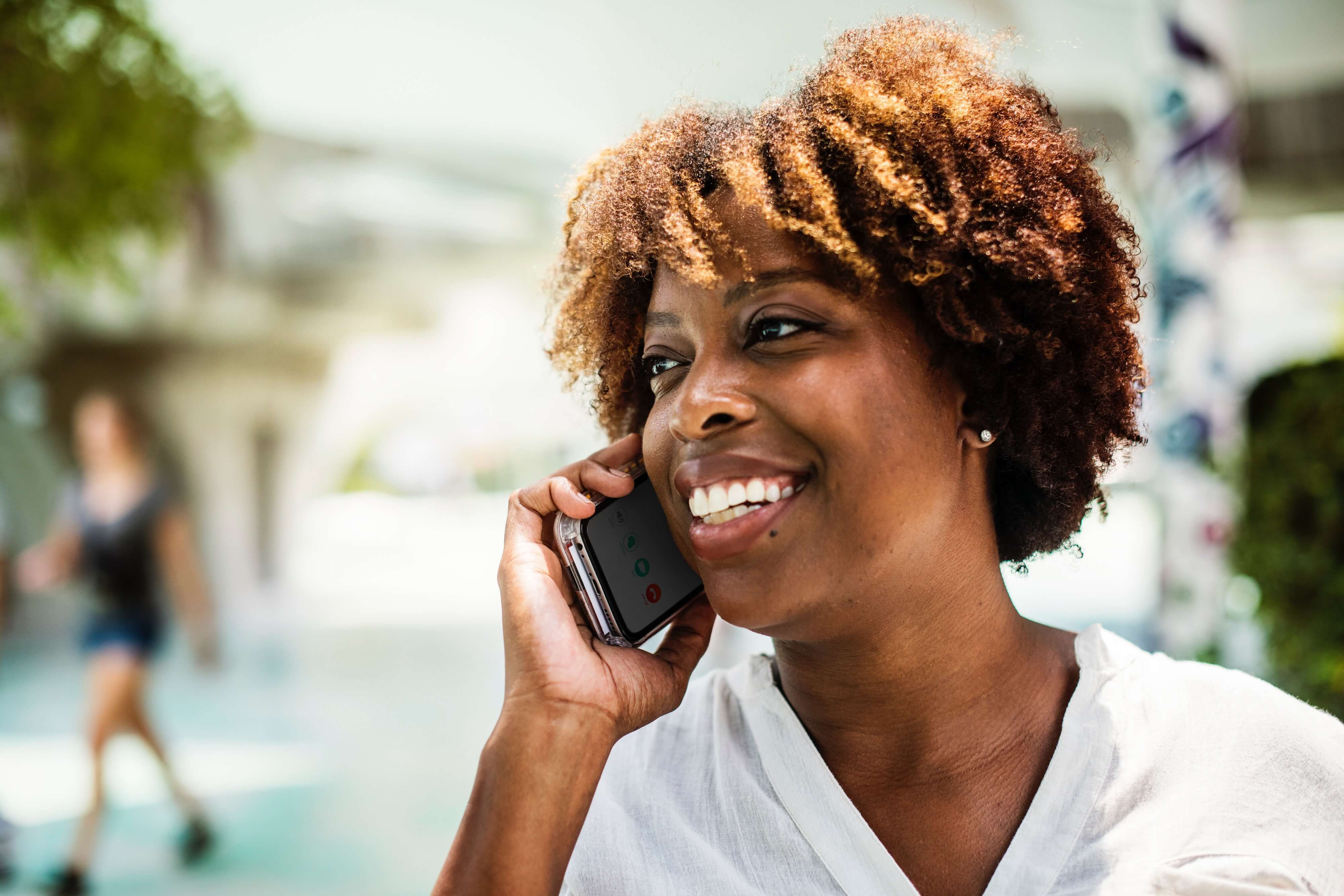 A woman on the phone, smiling. 